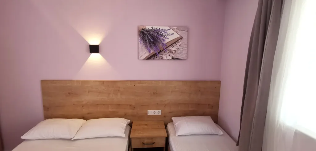 Motel Lavanda — lila duvarlar, lavanta tablosu ve bir çift, bir tek yataklı oda